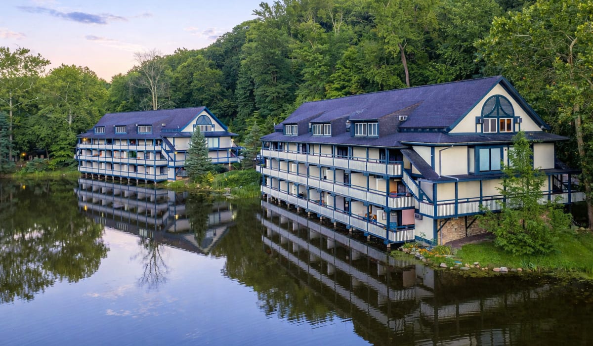 Lakefront apartment buildings reflected in calm water at Merriman Valley Apartments and Townhomes in Akron, Ohio