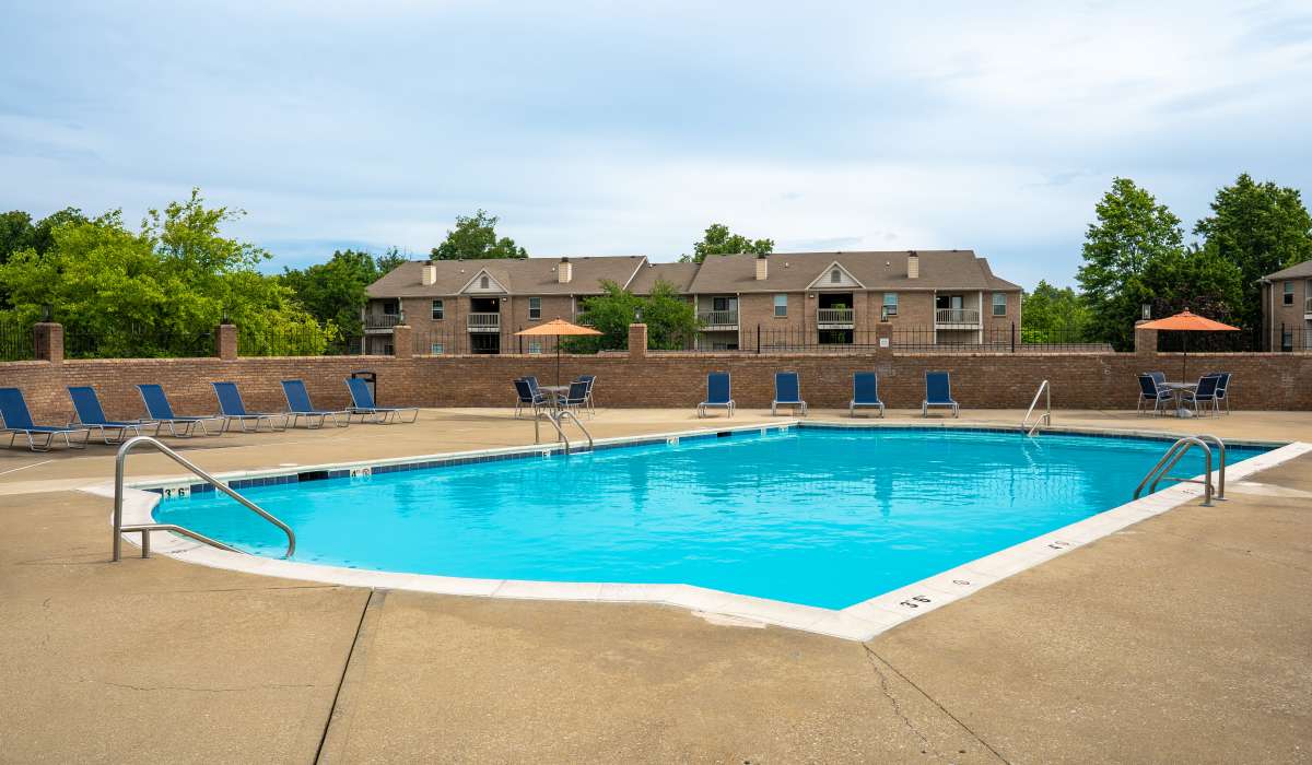 Sparkling pool surrounded by lounge chairs and shaded seating areas at Burlington Oaks in Burlington, Kentucky