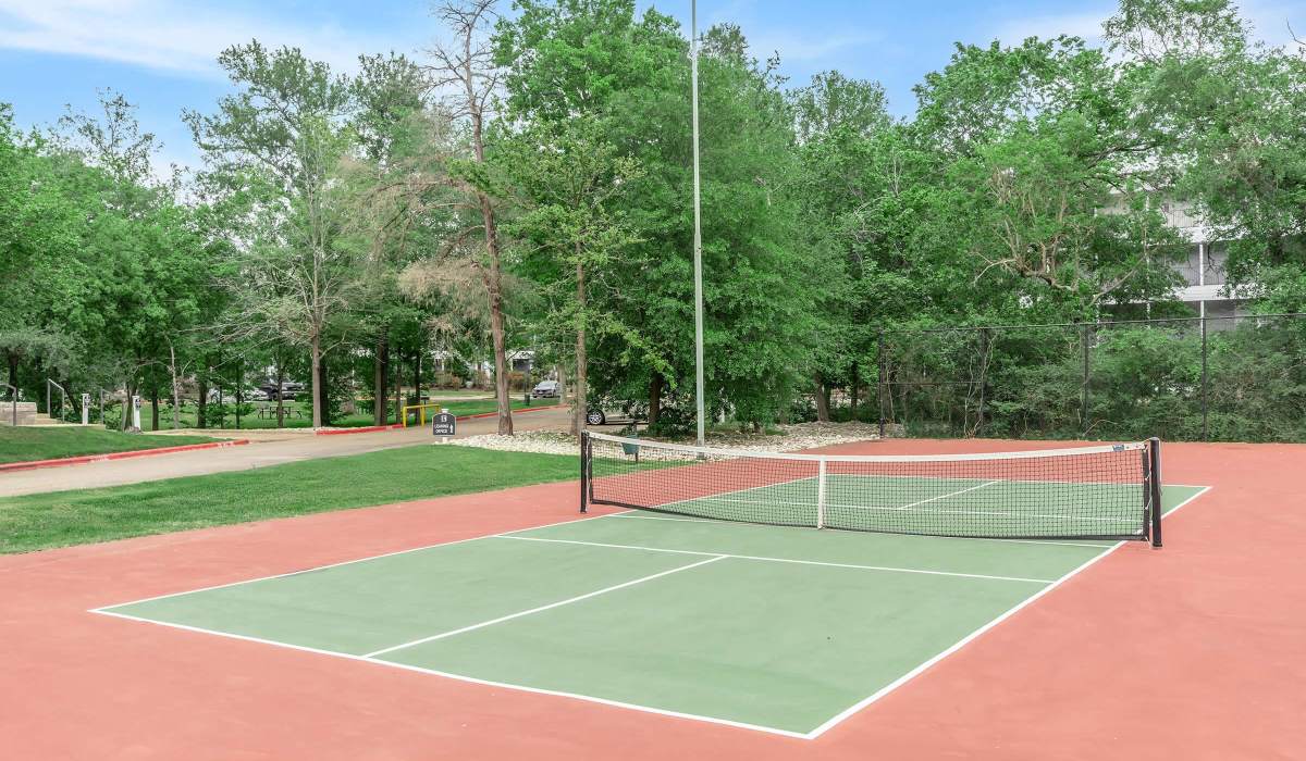 Modern green tennis court with red surface at The Element in Bryan, Texas