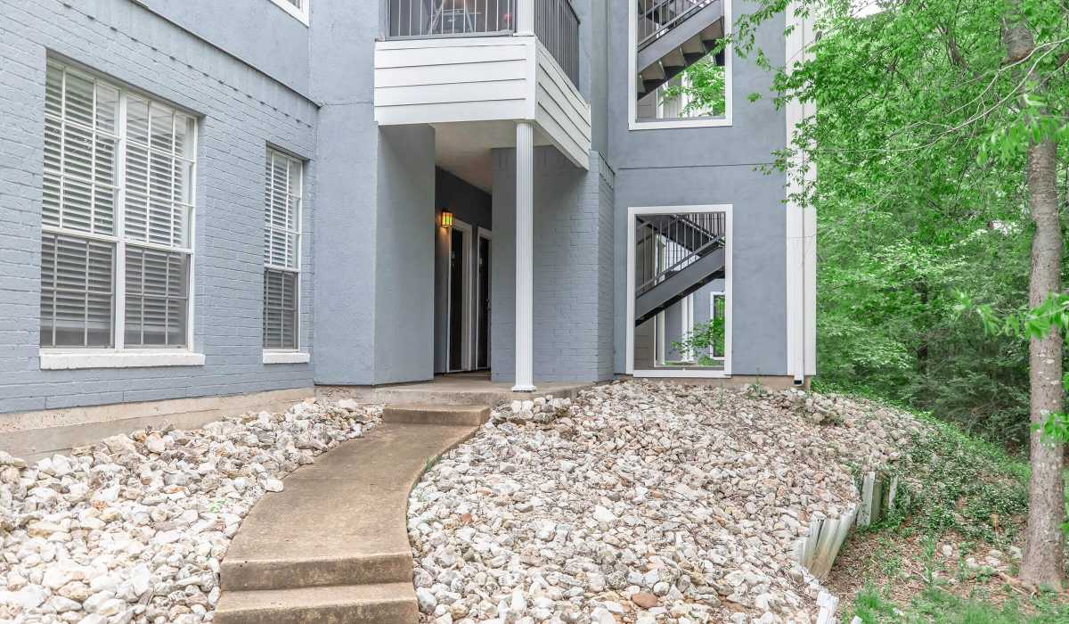 Modern gray building with stone pathway and greenery at The Element in Bryan, Texas