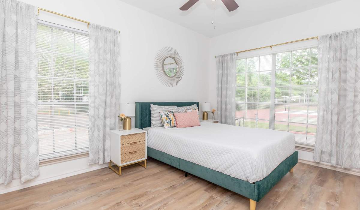 Modern green upholstered bed with decorative pillows at The Element in Bryan, Texas