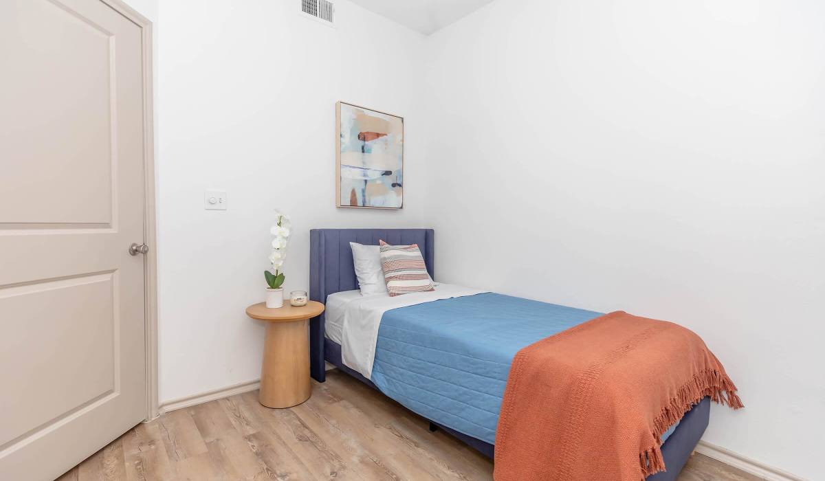 Modern single bed with blue and orange bedding at The Element in Bryan, Texas