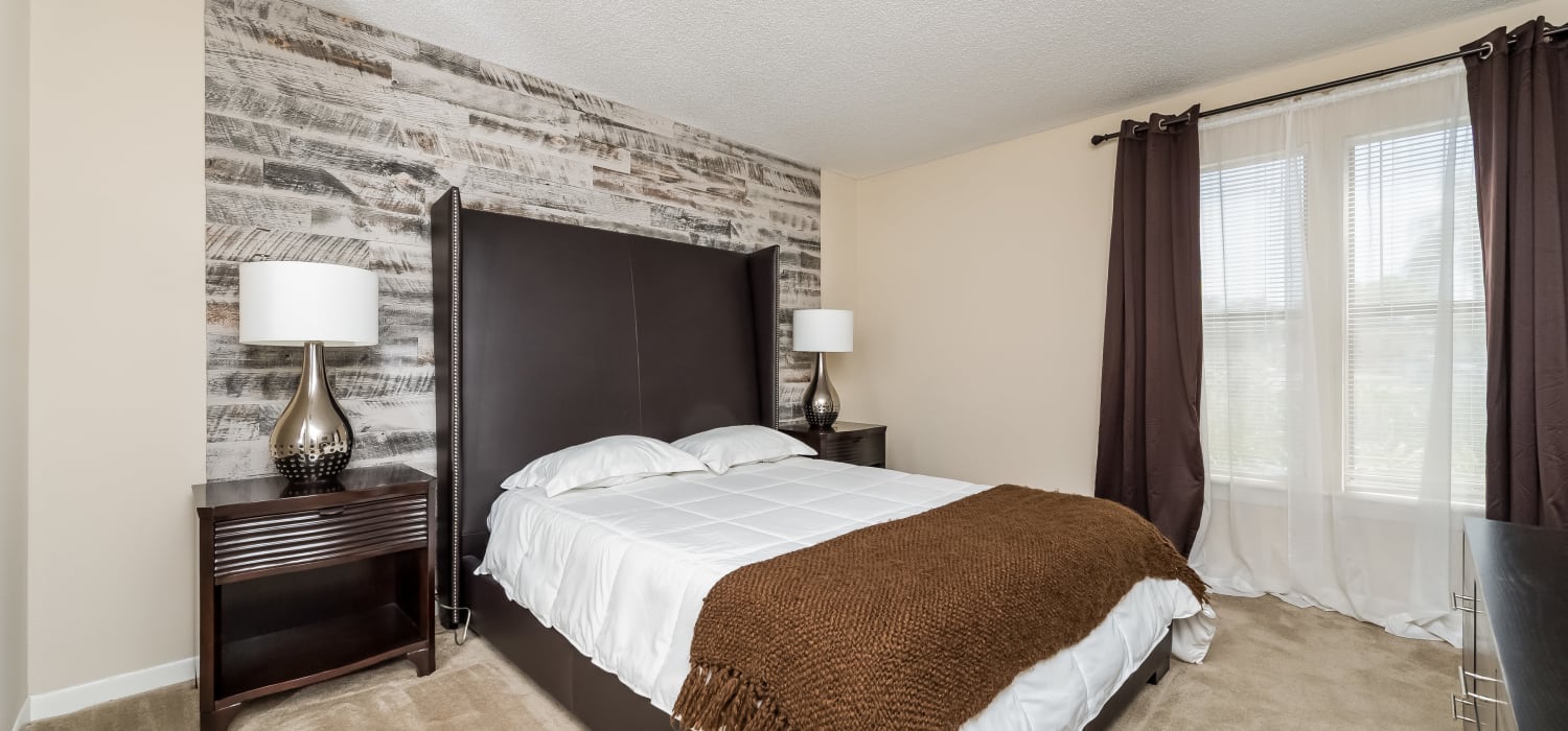 Master bedroom with plush carpeting and a textured accent wall in a model home at Tuscany Pointe at Tampa Apartment Homes in Tampa, Florida