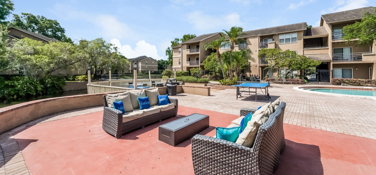 Outdoor lounge space and a ping pong table by the pool at Tuscany Pointe at Tampa Apartment Homes in Tampa, Florida
