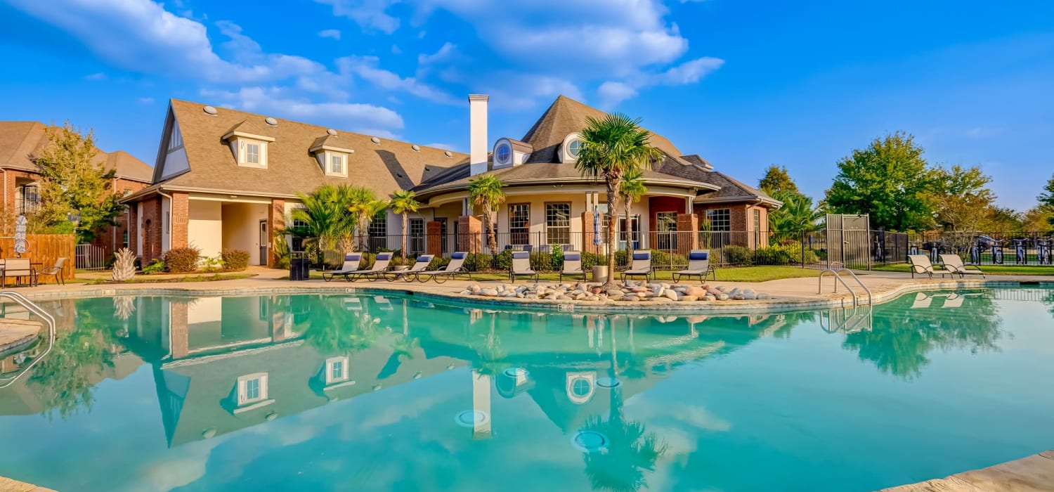 Sparkling swimming pool and clubhouse at Chateau Mirage Apartment Homes in Lafayette, Louisiana