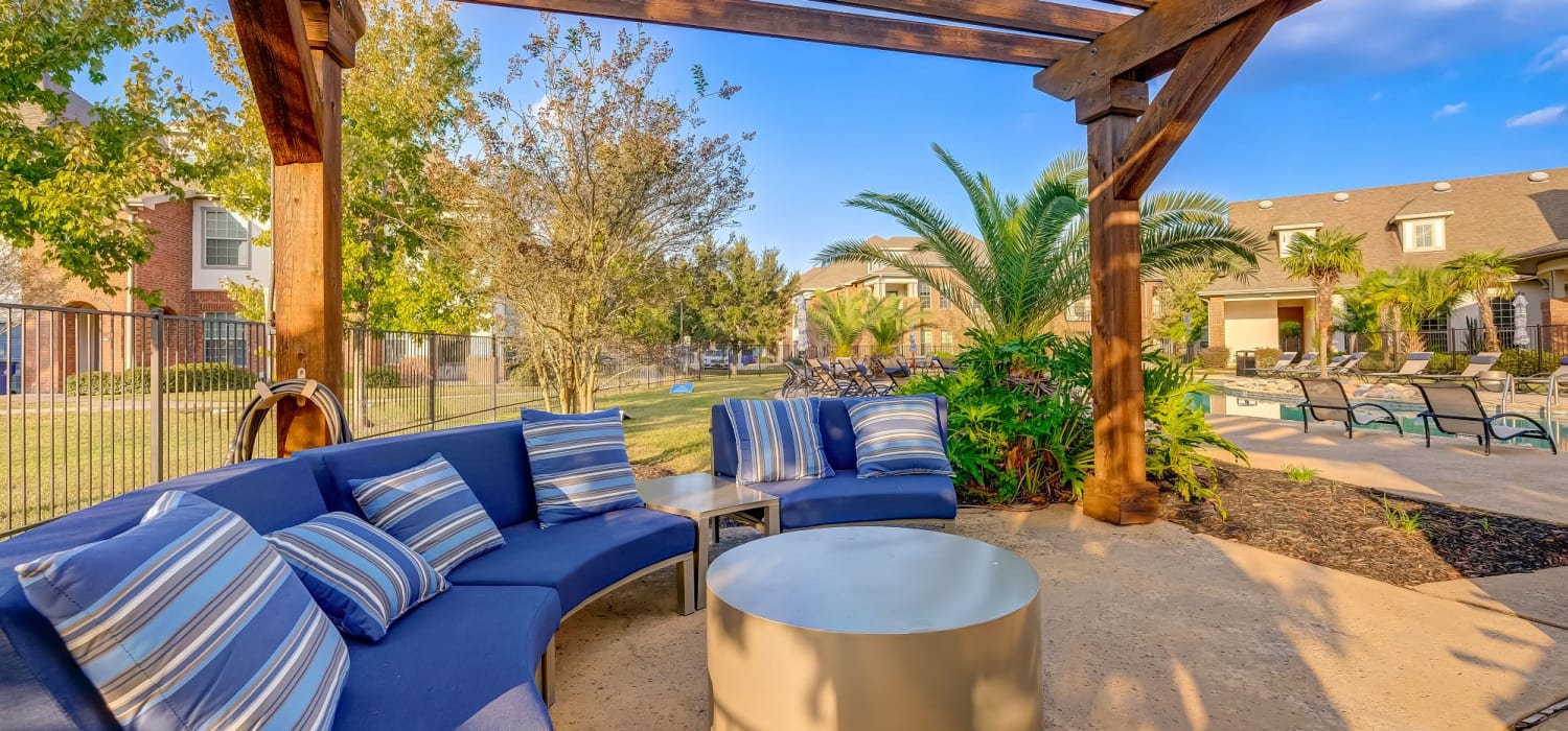 Comfortable outdoor patio seating with a fire place under a gazebo at Chateau Mirage Apartment Homes in Lafayette, Louisiana