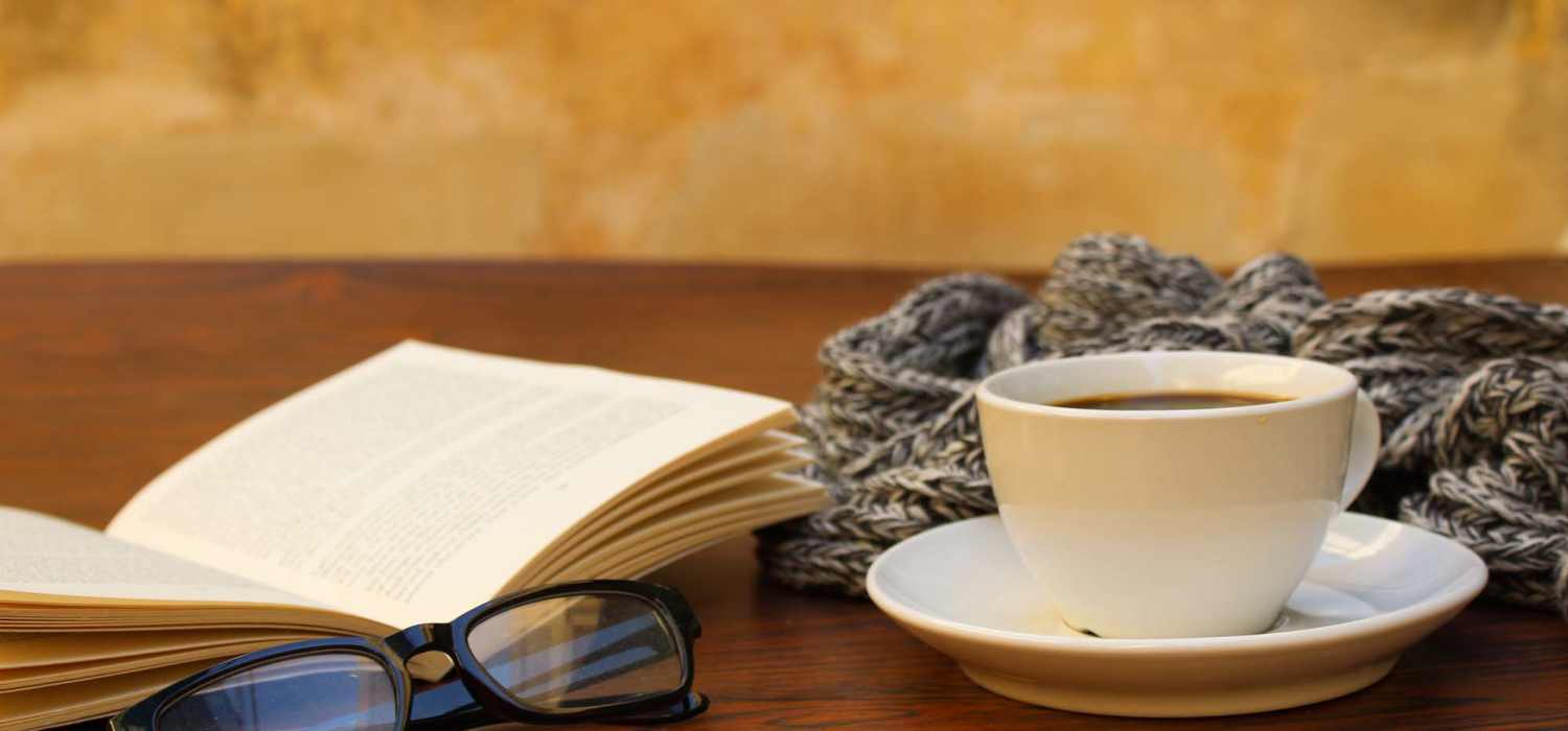 Close-up shot of a cup of Coffee beside a book at Knoll Creek Apartments in Waterloo, Indiana