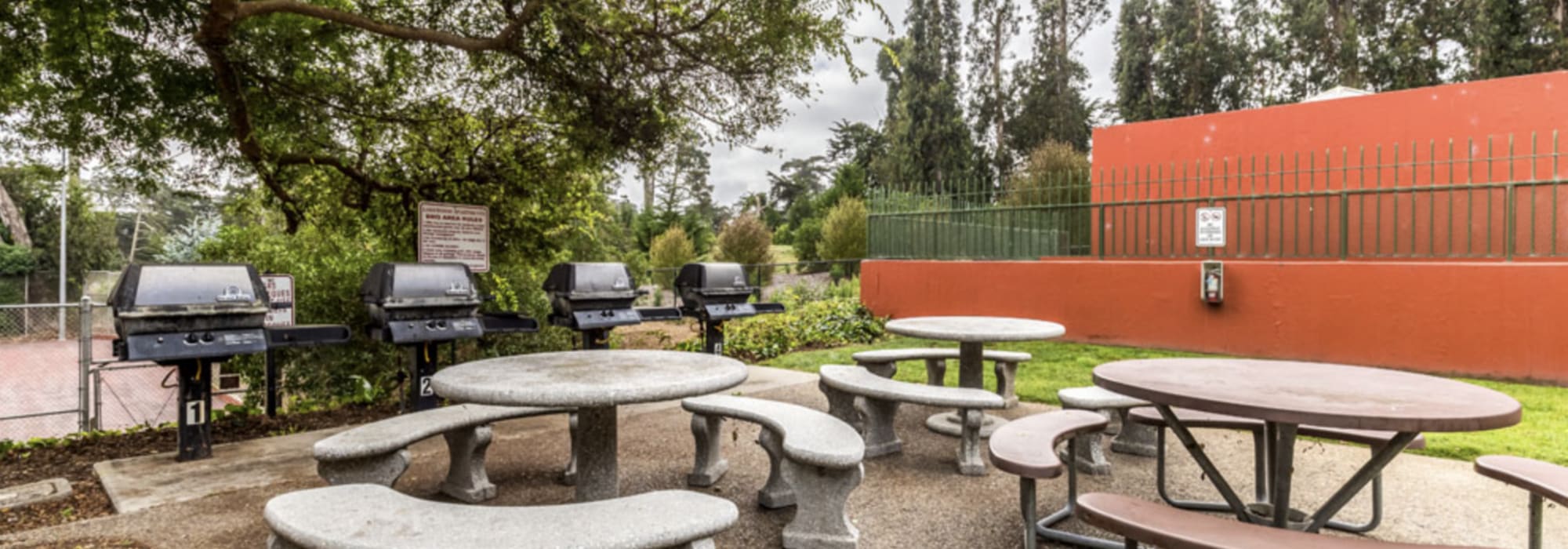 Outdoor grill station with picnic table at Lakewood Apartments at Lake Merced in San Francisco, California