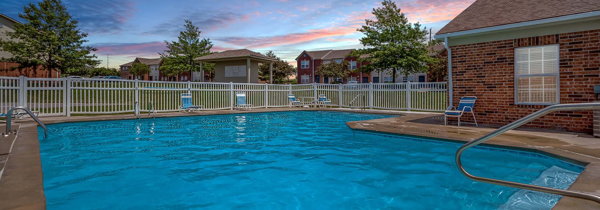 Pool deck with lounge chairs and resident clubhouse at Crossroads of Lee's Summit in Lees Summit, Missouri