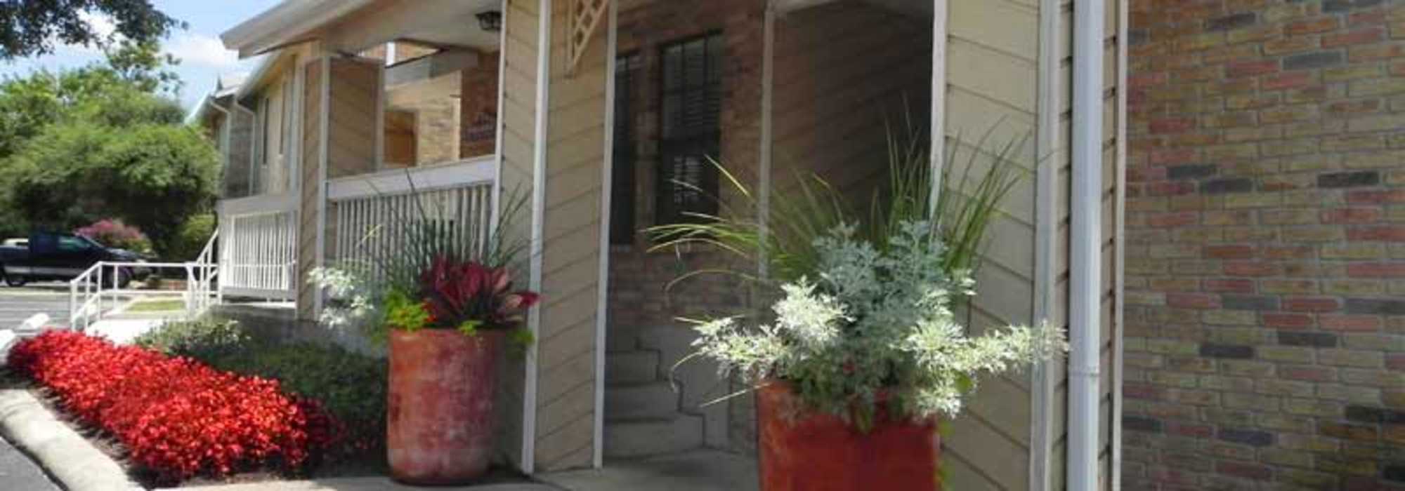 Entrance of the apartment building with flowers and greenery at Highcrest in San Marcos, Texas