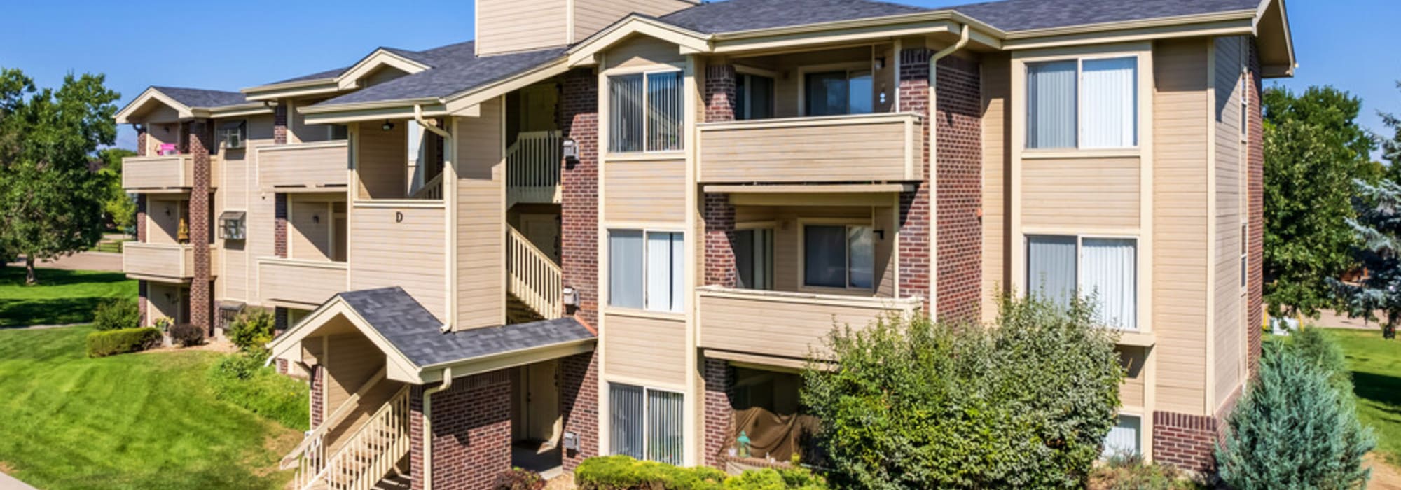 View of exterior of apartments and green lawn at UTE Creek Apartments in Longmont, Colorado  