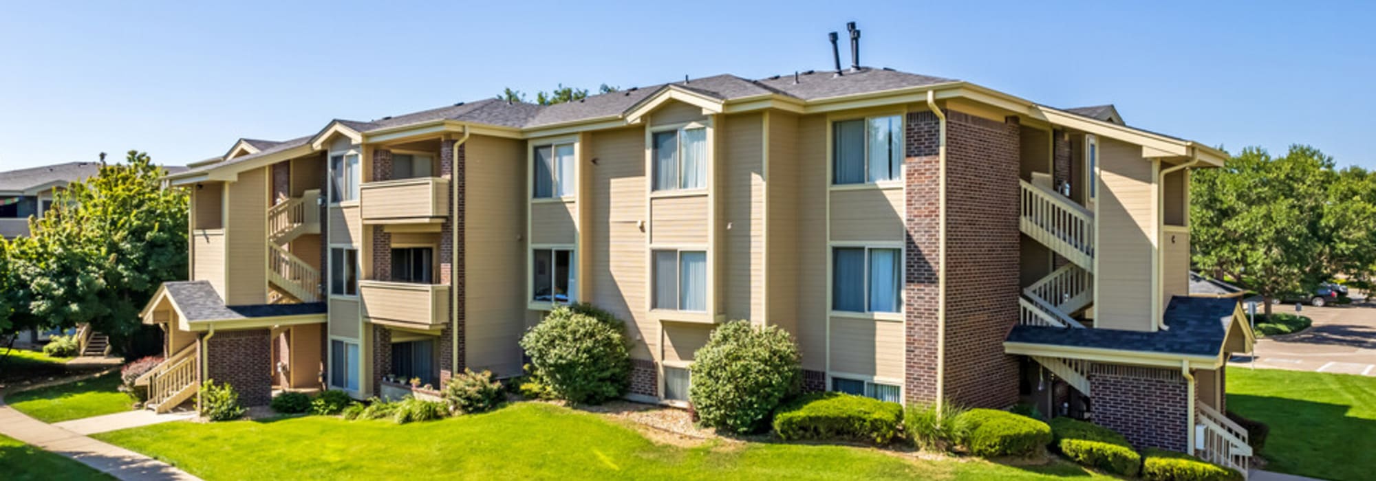 View of green lawn and trees surrounding the community at UTE Creek Apartments in Longmont, Colorado
