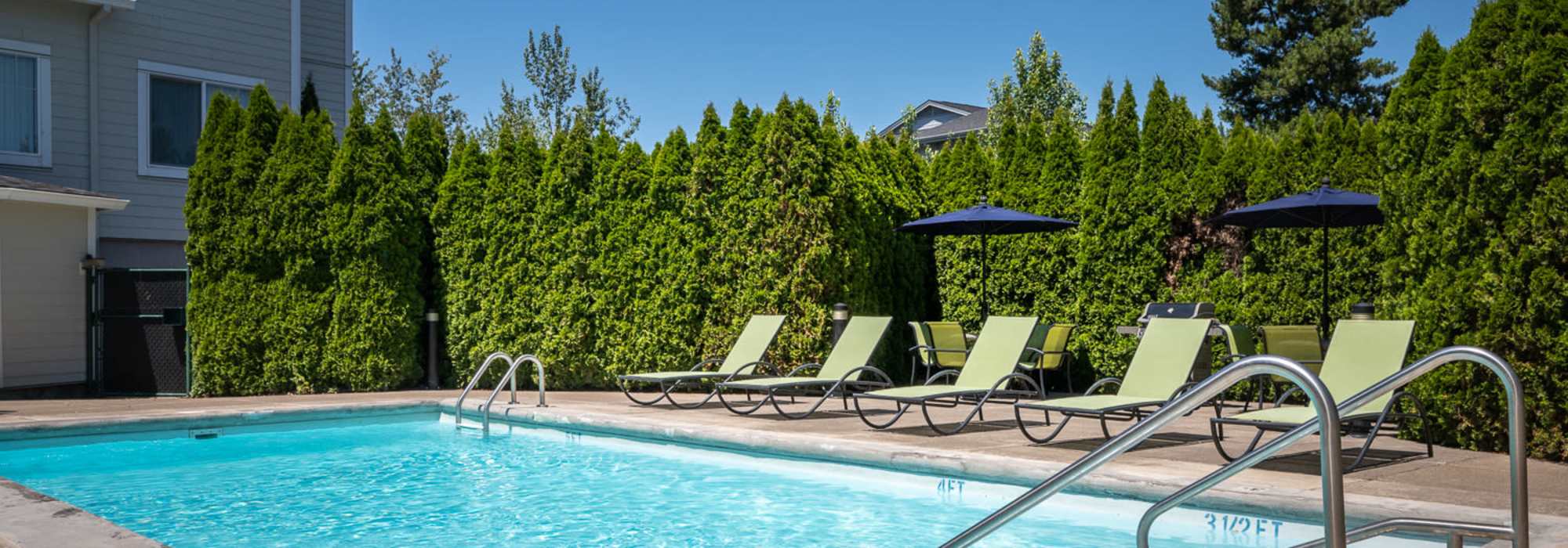 Swimming pool with lounge chair at Chinook Way Apartments in Fairview, Oregon