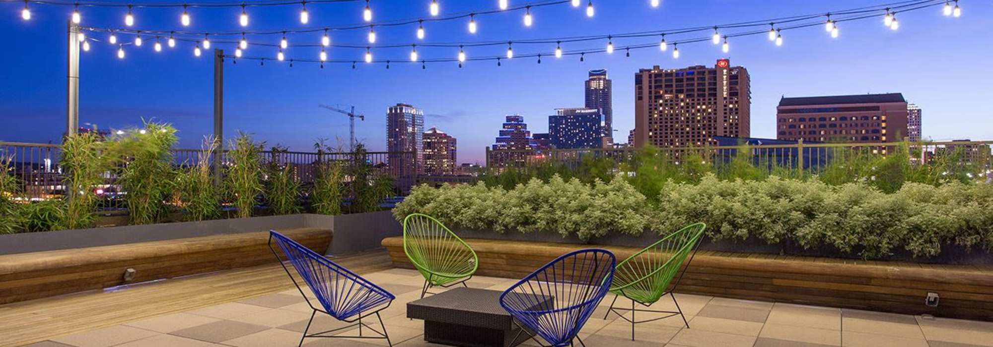 Rooftop patio with string lights, green plants, and colorful chairs at Corazon in Austin, Texas