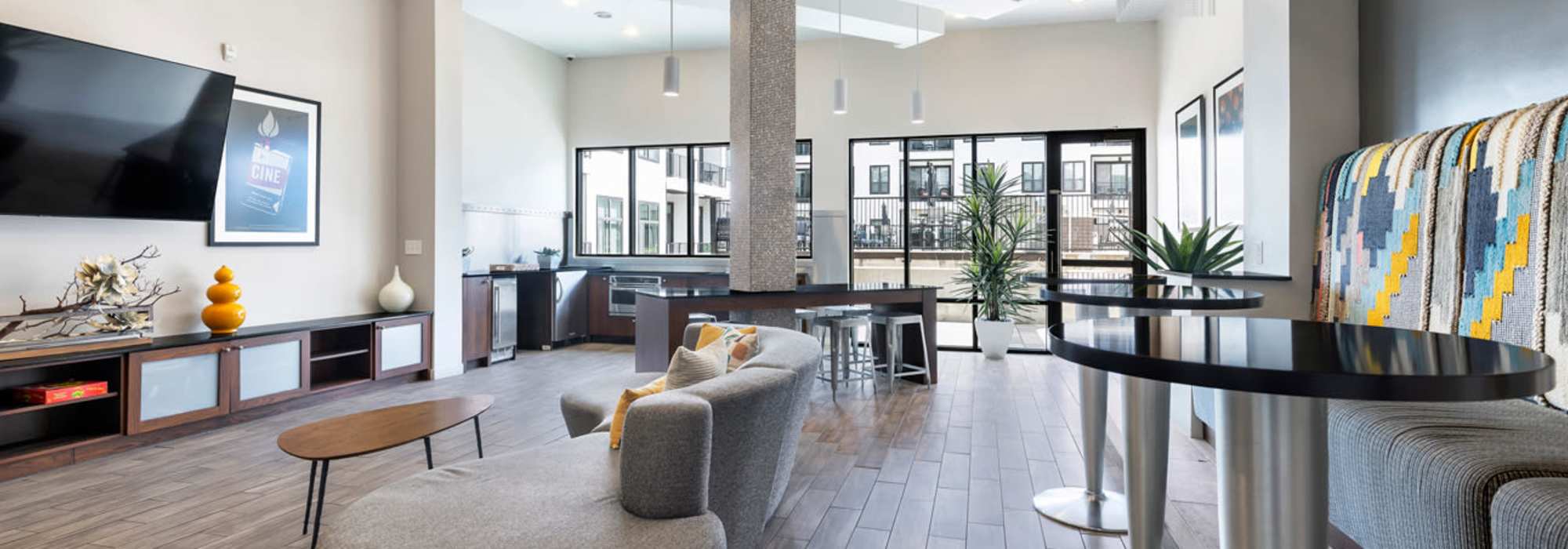 Modern community lounge with wood-style flooring and large windows at Corazon in Austin, Texas