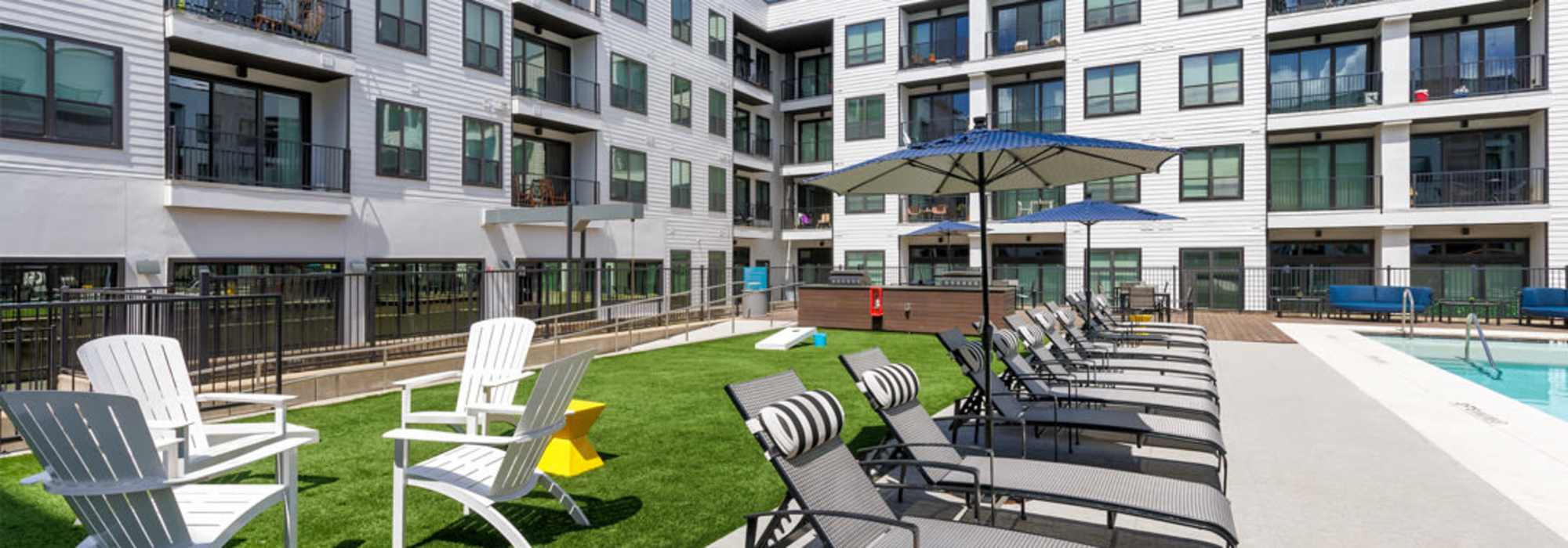 Resort-style pool area with lounge chairs and umbrellas at Corazon in Austin, Texas