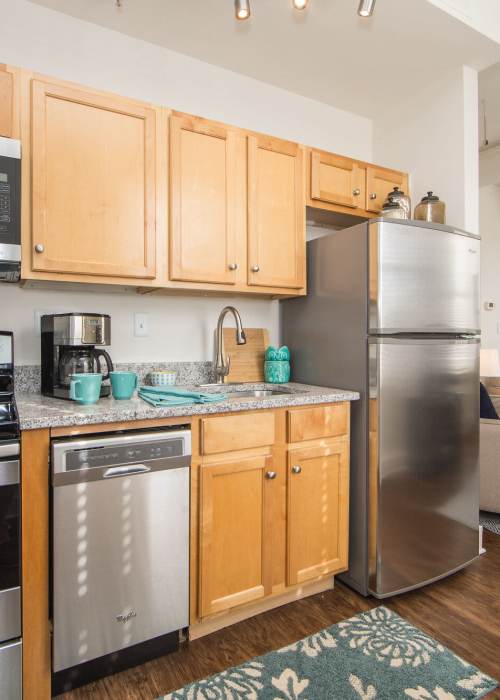Fully equipped kitchen with refrigerator and wood cabinetry atGrace and Monroe Apartments in Richmond, Virginia