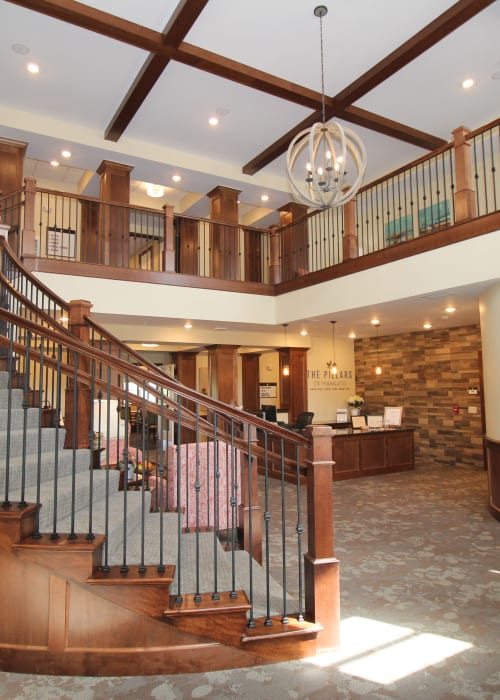 Beautiful lobby with large wooden staircase and hanging light fixture at The Pillars of Mankato in Mankato, Minnesota