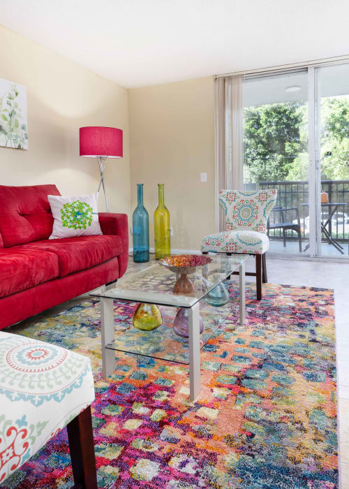 A red couch and colorful rug in a model apartment living room at Forest Place in North Miami, Florida