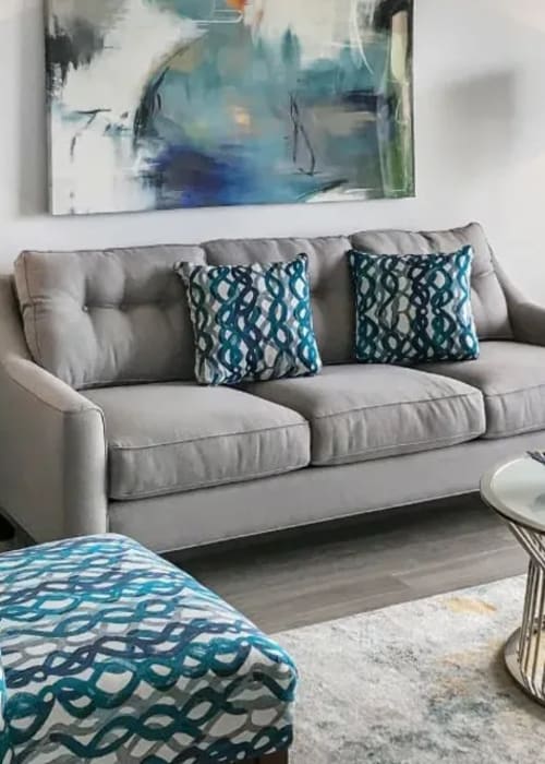 Grey couches with blue throw pillows in a furnished living room at Marina Del Mar in Sunny Isles Beach, Florida