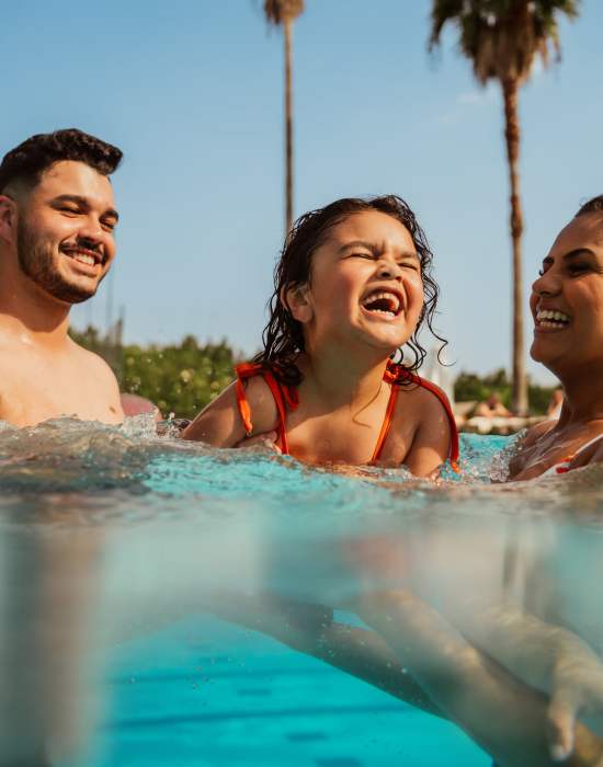 Father and mother swimming with toddler daughter in pool at The Indie Glendale Collection in Glendale, California
