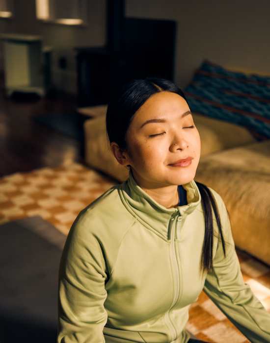 A women doing yoga on her bed facing to the sunlight at The Indie Glendale Collection in Glendale, California