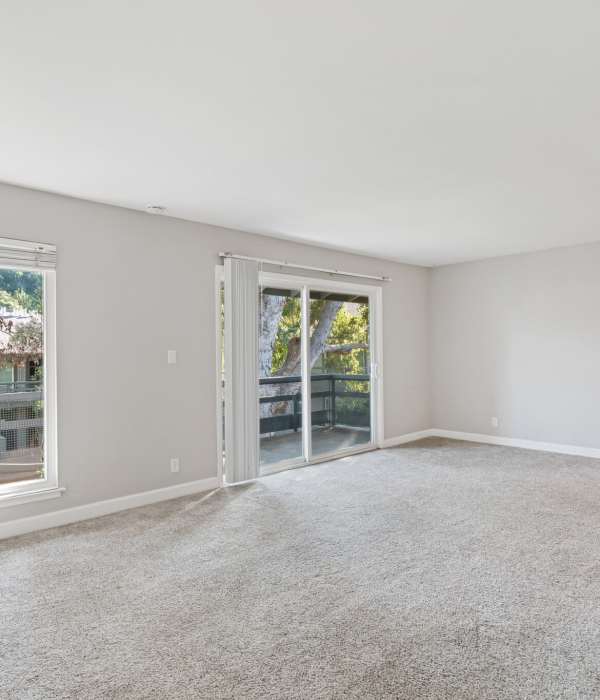 Carpeted living area with large windows at Hillside Garden in San Mateo in San Mateo, California
