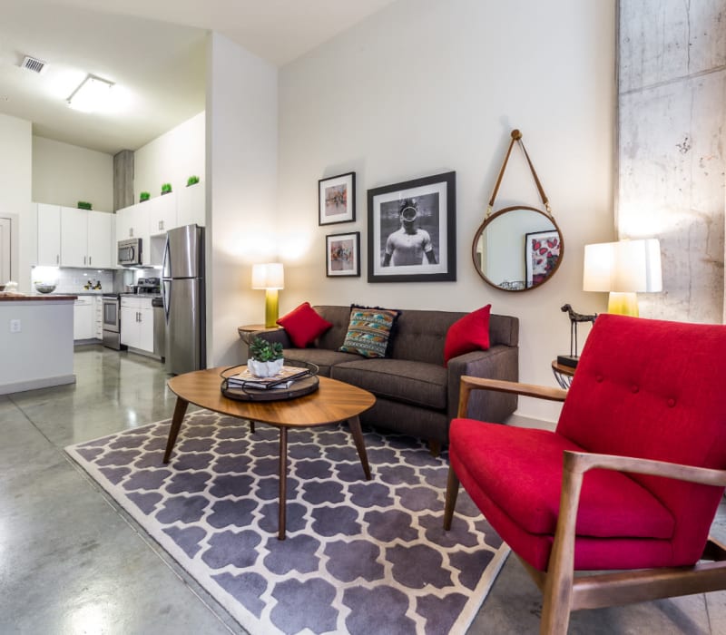Open living room with modern furnishings and bright kitchen in background at Marq on Burnet in Austin, Texas