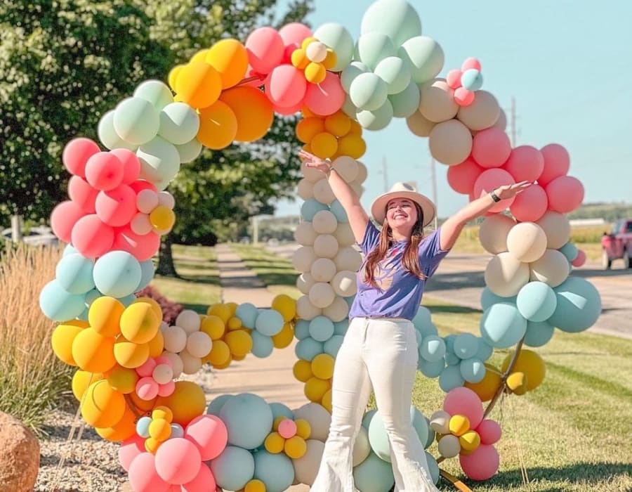 CLS Society member posing in front of a colorful balloon arch for an event at Campus Life & Style in Austin, Texas