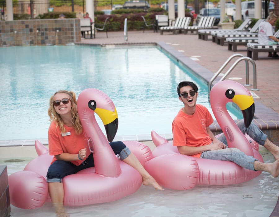 Campus Life & Style team members on flamingo floats in the pool of a Campus Life & Style Autograph Collection community