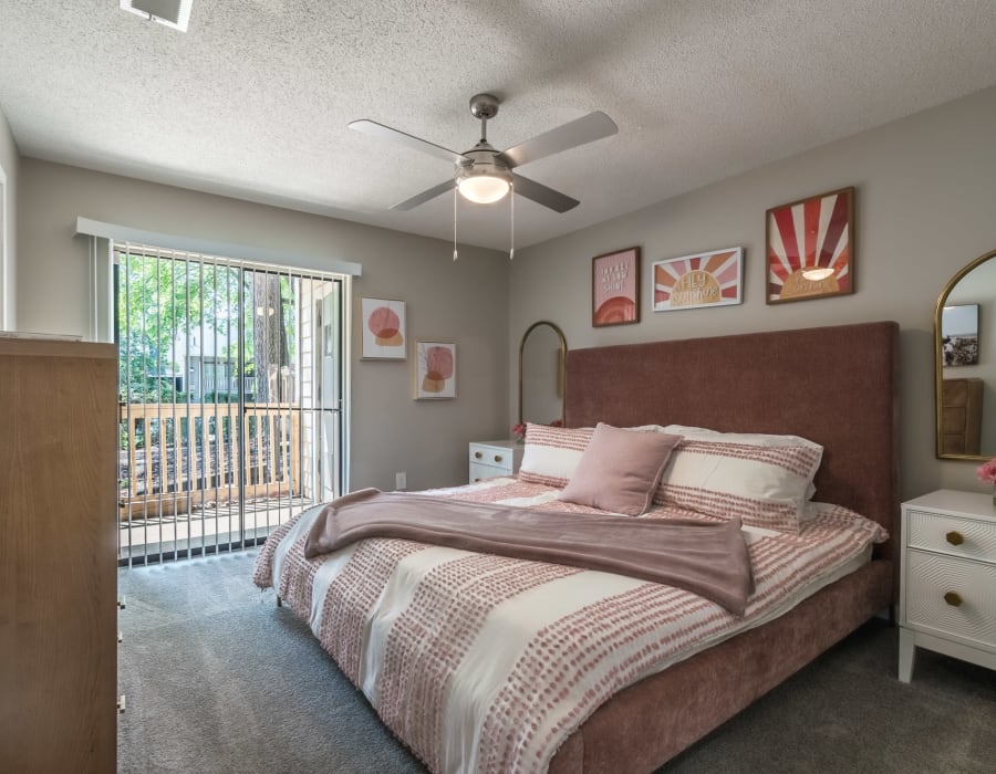 Model apartment bedroom with a queen bed and balcony at Edge at Lakeview in Memphis, Tennessee