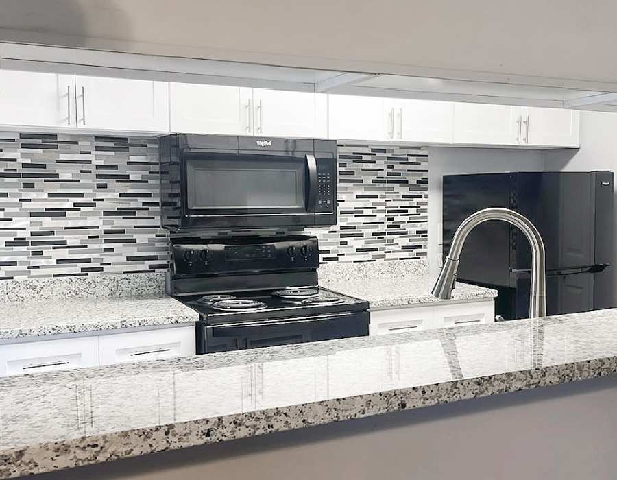 Kitchen island with waterfall faucet, and granite countertops at Oaks of Wimbledon in Spring, Texas, 