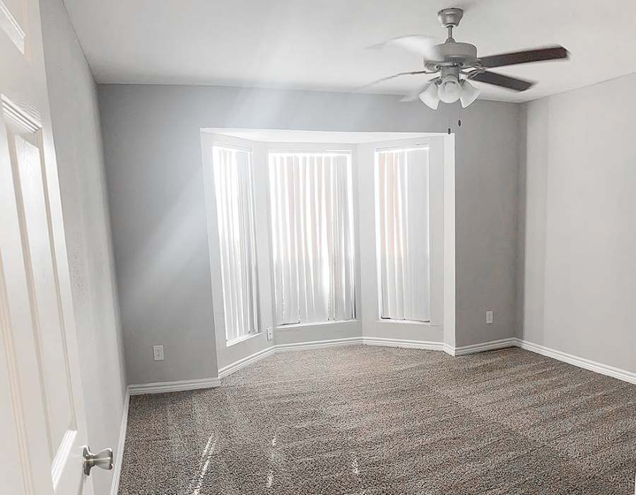Well-lit bedroom with large window, plush carpet, and ceiling fan at Oaks of Wimbledon in Spring, Texas, 