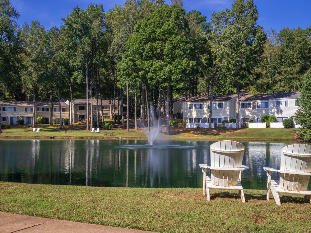 Two chairs facing the pond and apartment across it at Pinewood Station in Hillsborough, North Carolina