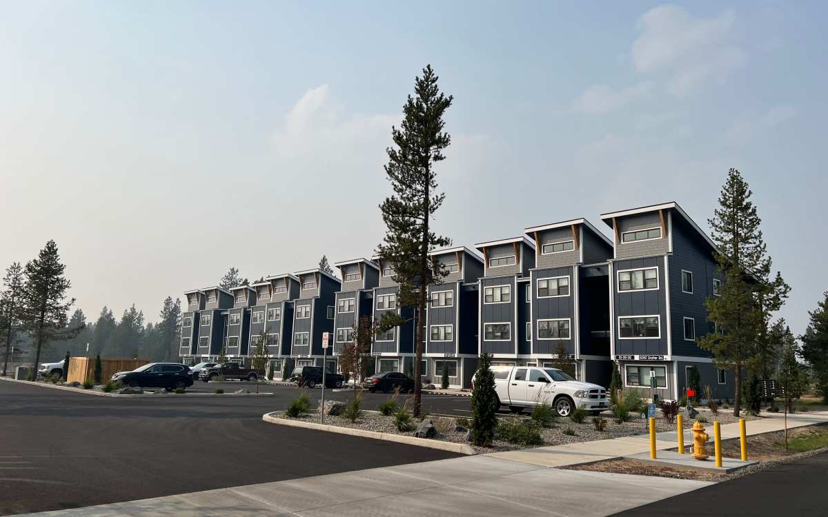 View of apartment buildings with a spacious parking lot situated in front at Pine View in La Pine, Oregon
