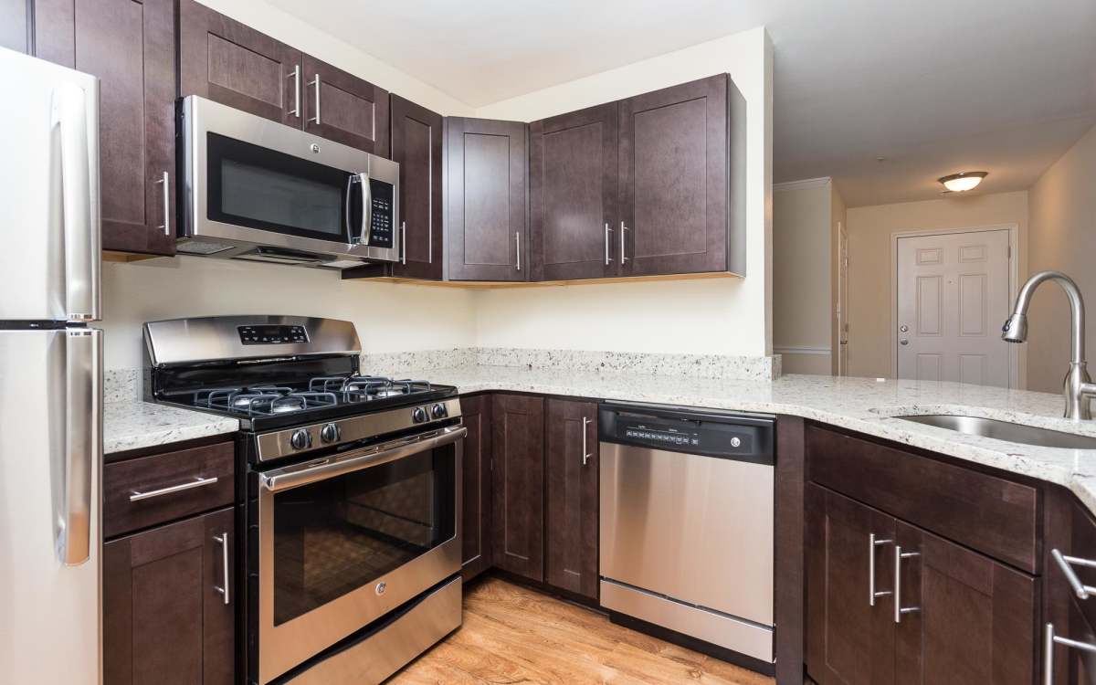 Modern kitchen with wooden cabinets, refrigerator and stainless-steel appliances at Beacon Place at Kentlands in Gaithersburg, Maryland
