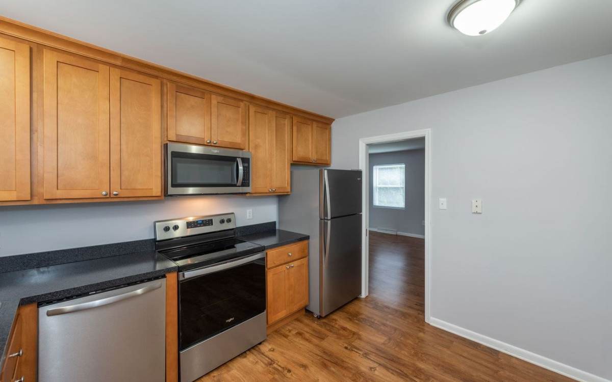 Modern kitchen with wooden cabinets and granite countertops at Signal Point Apartments in Mechanicsville, Virginia