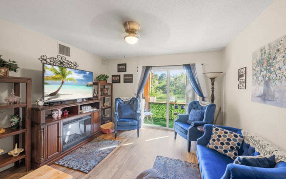 Living room with a TV and blue furniture at Pelican Isles Apartments in Sebastian,Florida