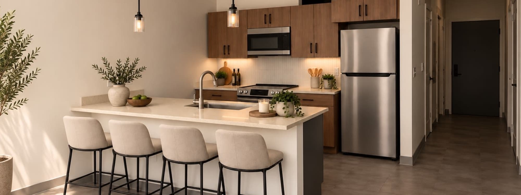 Kitchen with wood cabinets, stainless appliances and breakfast bar with three stools by a large window at Altitude on Main in Richmond, Virginia