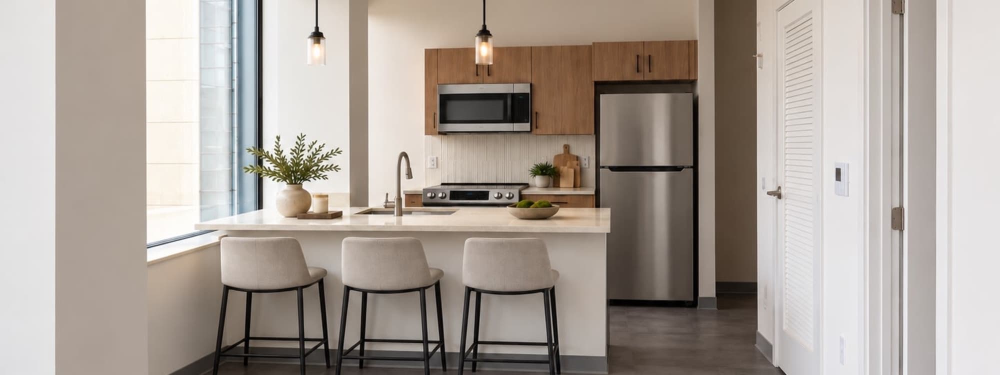 Kitchen with dark island, quartz counter, three stools and floor-to-ceiling city-view windows at Altitude on Main in Richmond, Virginia