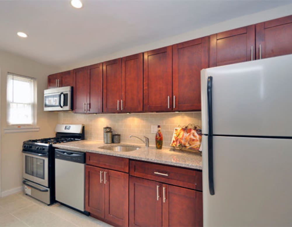 Cherry red wood cabinets and stainless steel appliances in the kitchen at Eagle Rock Apartments at Maplewood in Maplewood, New Jersey