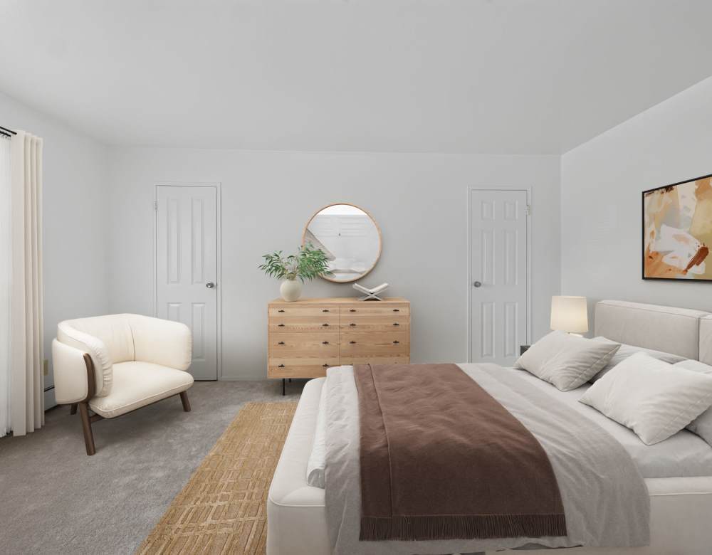 Bedroom with cozy bed and carpert flooring at Eagle Rock Apartments at Patchogue Preserve in East Patchogue, New York