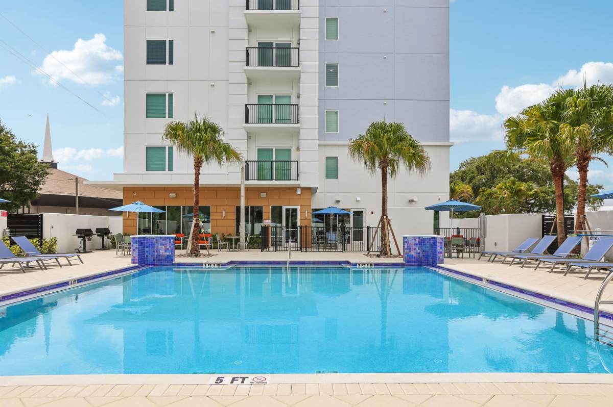 Sparkling pool with trees and lounge chairs at The Breeze in Winter Haven, Florida