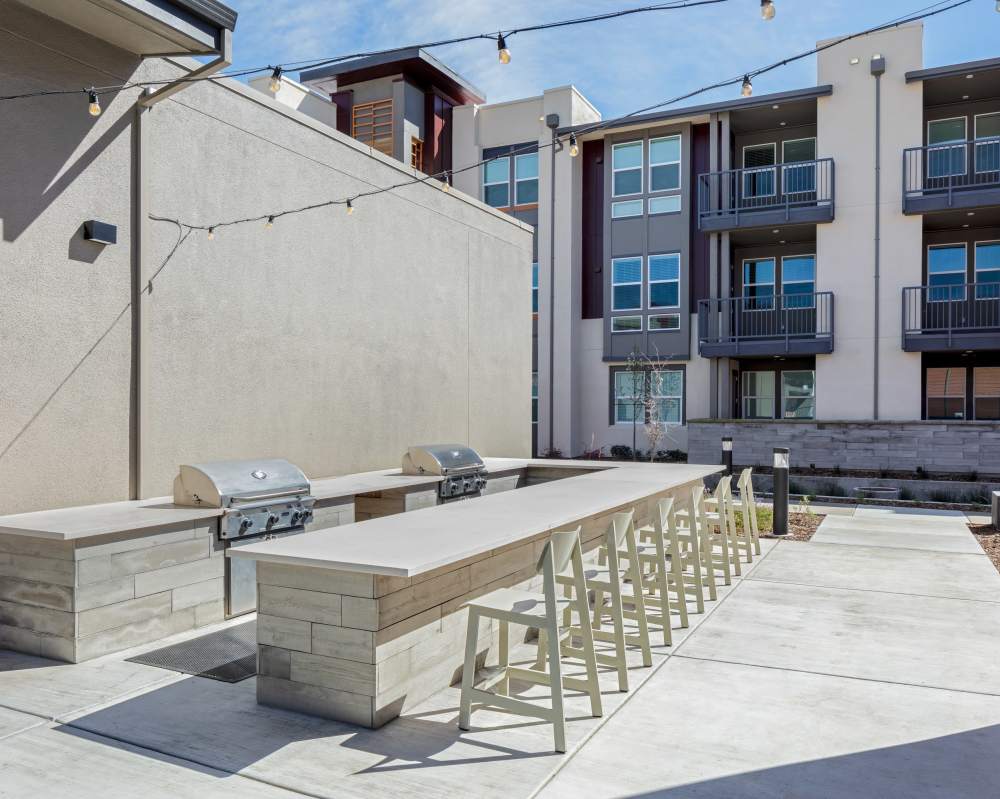 Pet-Friendly Apartments In Napa, CA - SoCo Apartments - Outdoor BBQ Area With Two Grills, Stringed Lights, Plenty Of Seating, And Lots Of Counter Space