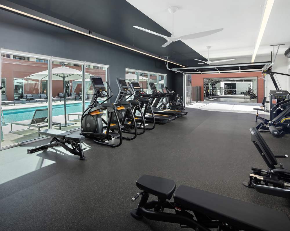 Apartments In Napa, CA With In-Unit Washer And Dryer - SoCo Apartments - Fitness Center Equipped With Cardio Machines, Workout Benches, And Strength Training Machines With A View Of The Pool