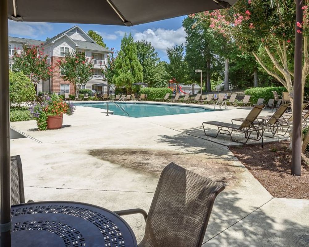 Patio table by the sunny swimming pool at Heather Park Apartment Homes in Garner, North Carolina
