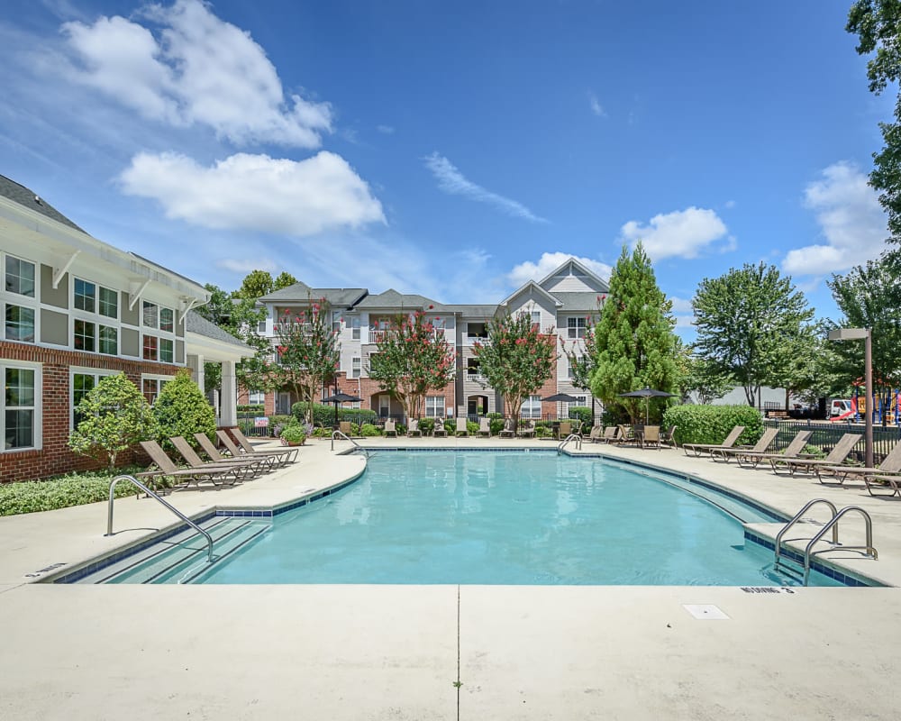 Sparkling swimming pool and sundeck with lounge seating at Heather Park Apartment Homes in Garner, North Carolina