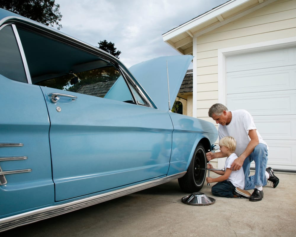 A father and son changing a tire on a classic care being stored at STOR-N-LOCK Self Storage in Thornton, Colorado