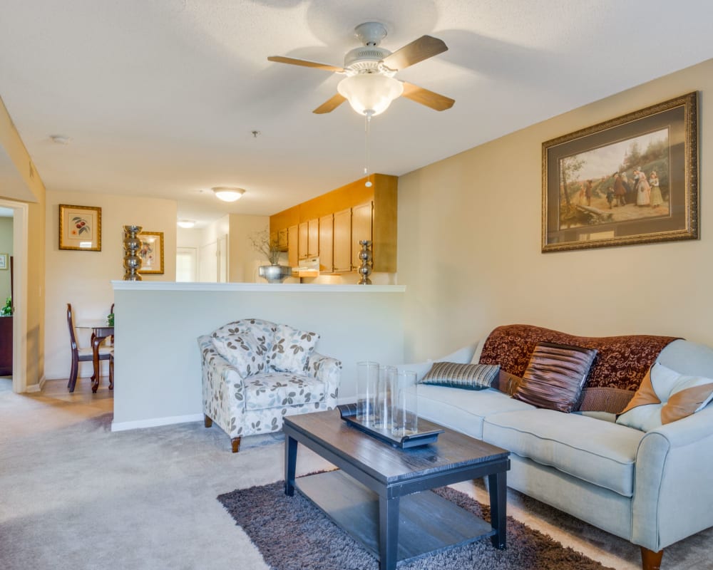 A living room with a ceiling fan at Woodbrook Apartment Homes in Monroe, North Carolina
