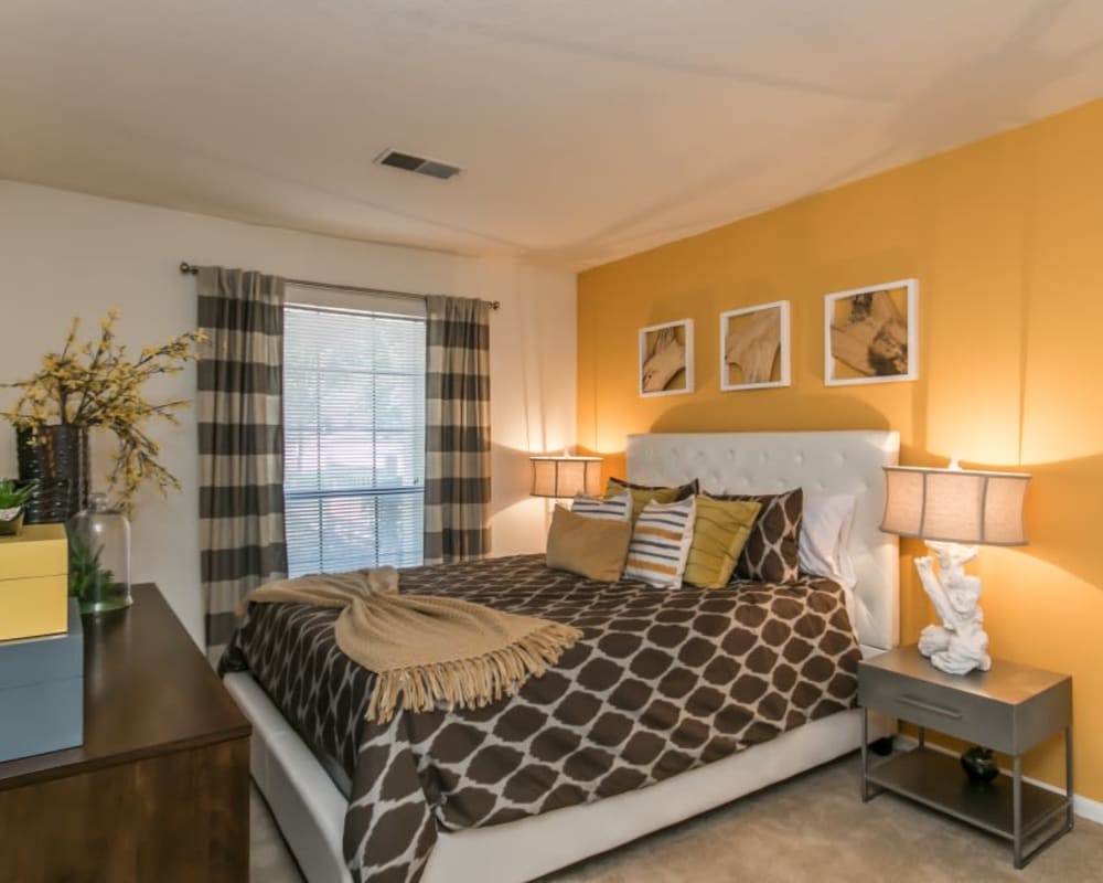 Well decorated model bedroom with warm yellow accent wall at St. Andrews Commons Apartment Homes in Columbia, South Carolina